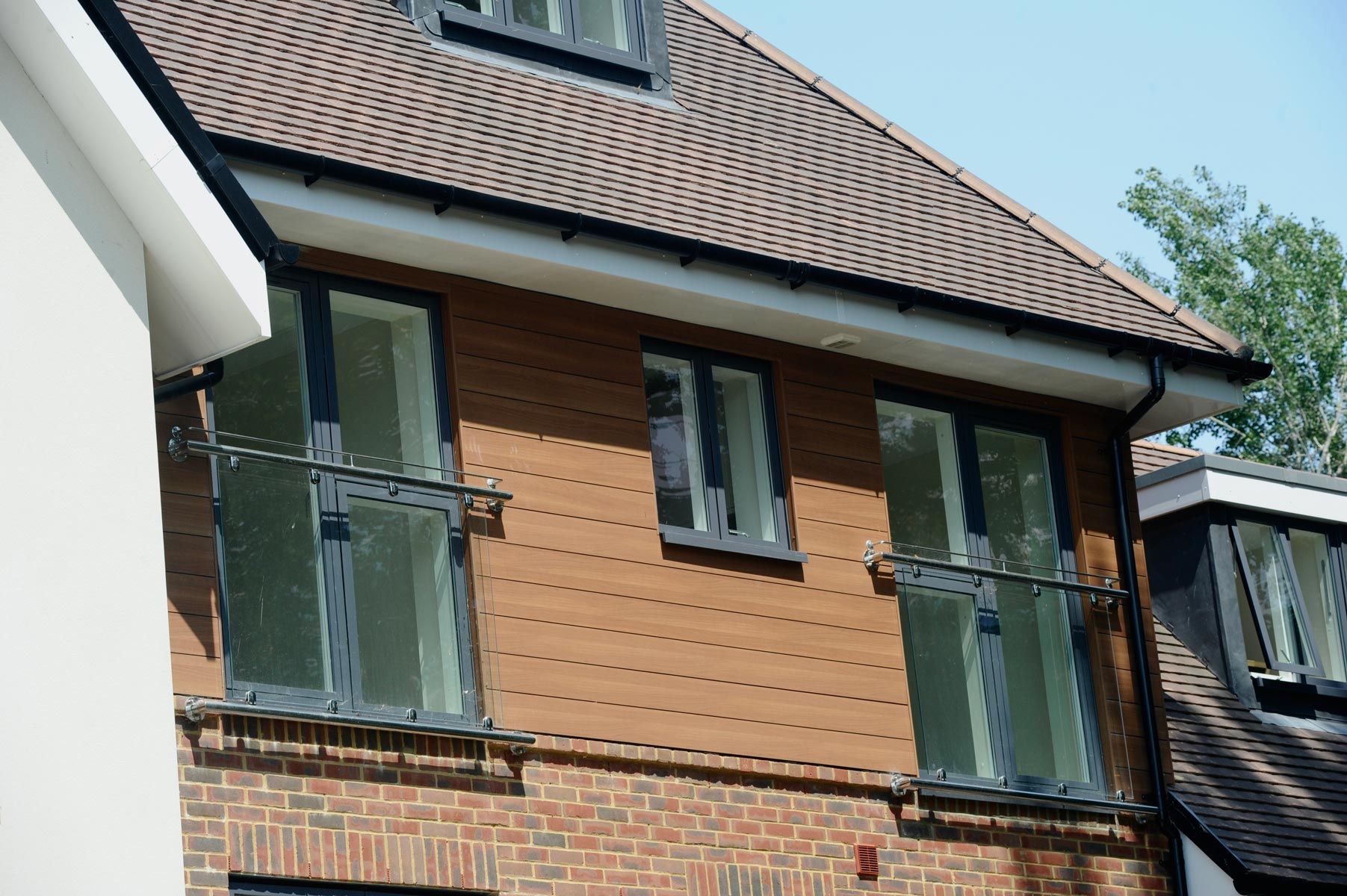 Braune Trespa Fassadenpaneele. Die Fenster sind anthrazit.