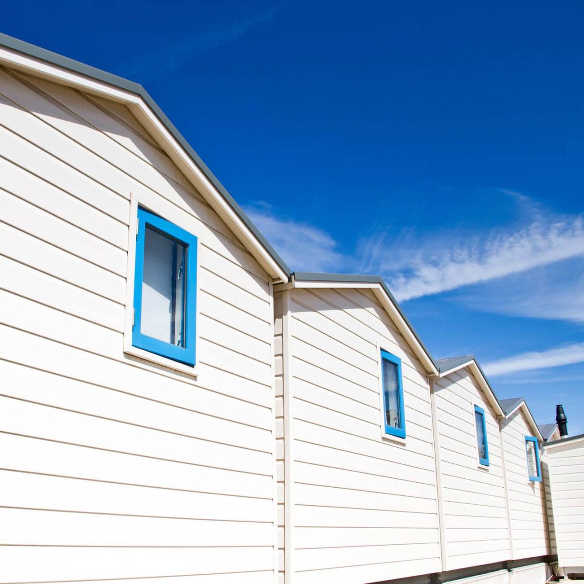 Ferienhausverkleidung mit Stülpschalungspaneelen von vinyPlus in Holzoptik und der Farbe Cremeweiß.