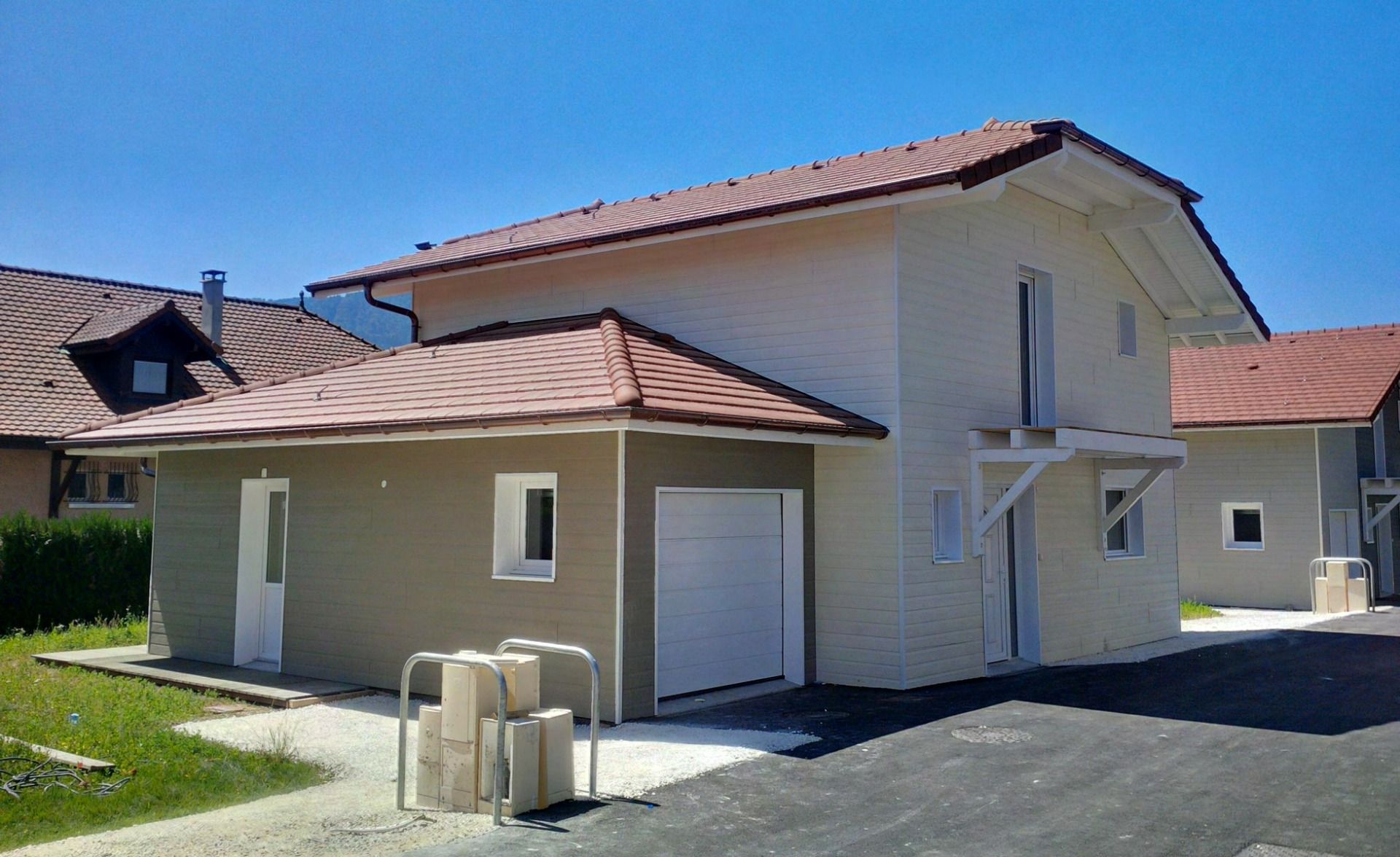Garage mit Walmdach am Haus. Die Fassadenpaneele aus Holz wurden farblich zur Hausfassade abgesetzt.