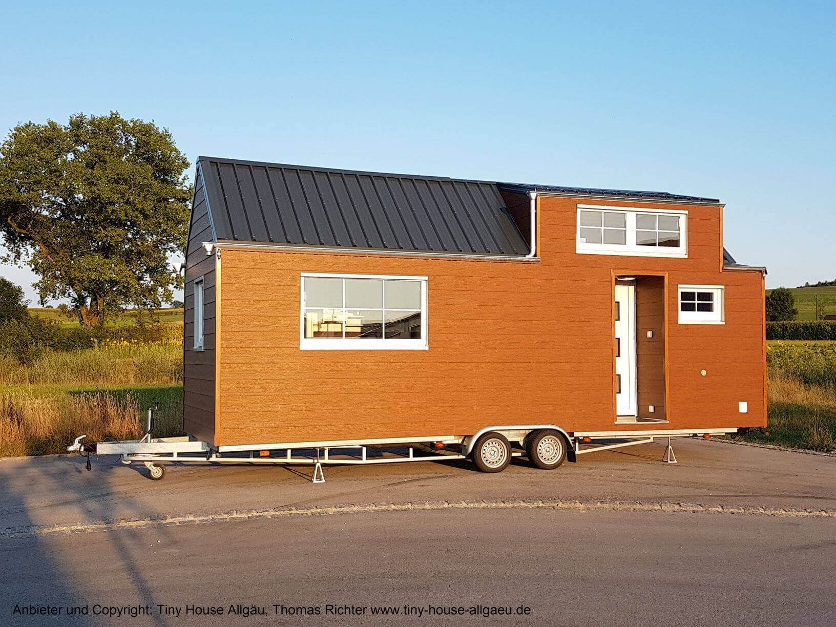 Tiny House mit einer Kerrafront Fassade in golden oak. Das Tiny House kann entweder als Mobilheim-Variante auf einem Stahlrahmen oder als Mobilheim-Chassis fahrbar mit Straßenzulassung auf einem Trailer gebaut werden.