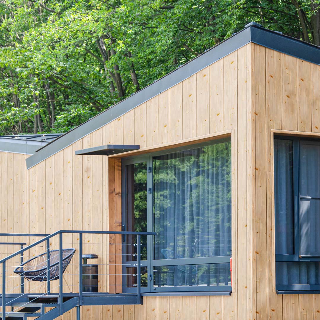 Moderne Einfamilienhäuser. Die Fassadenverkleidung in senkrechter Verlegung besteht aus einer Kombination von den Farben Jura Pine und Kitami Oak