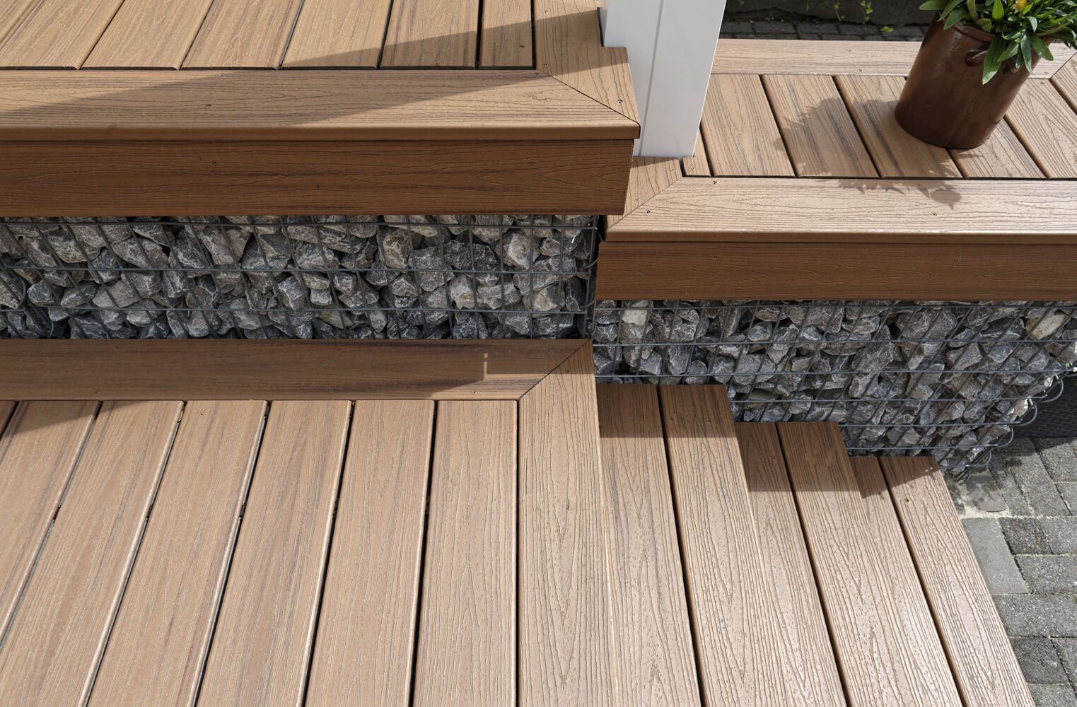 Bräunliche Trex Terrassendielen uns Gabionen im Detail.